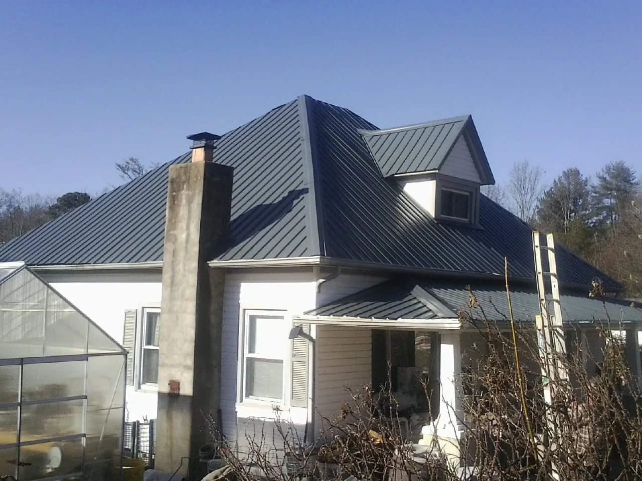 Dark blue standing seam metal roof on a white farmhouse with dormer — Slate & Tile Roof Repair by Roofing Brothers in Black Diamond