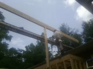 Carpenter setting a ridge beam over a new addition frame — Ice Dam Removal by Roofing Brothers in Black Diamond
