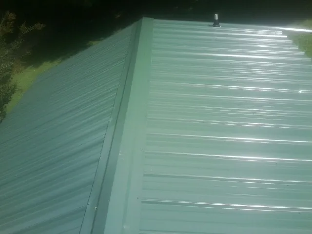 New green metal panels meeting at the ridge of a roof — Flat Roof Repair work by our crew in Black Diamond