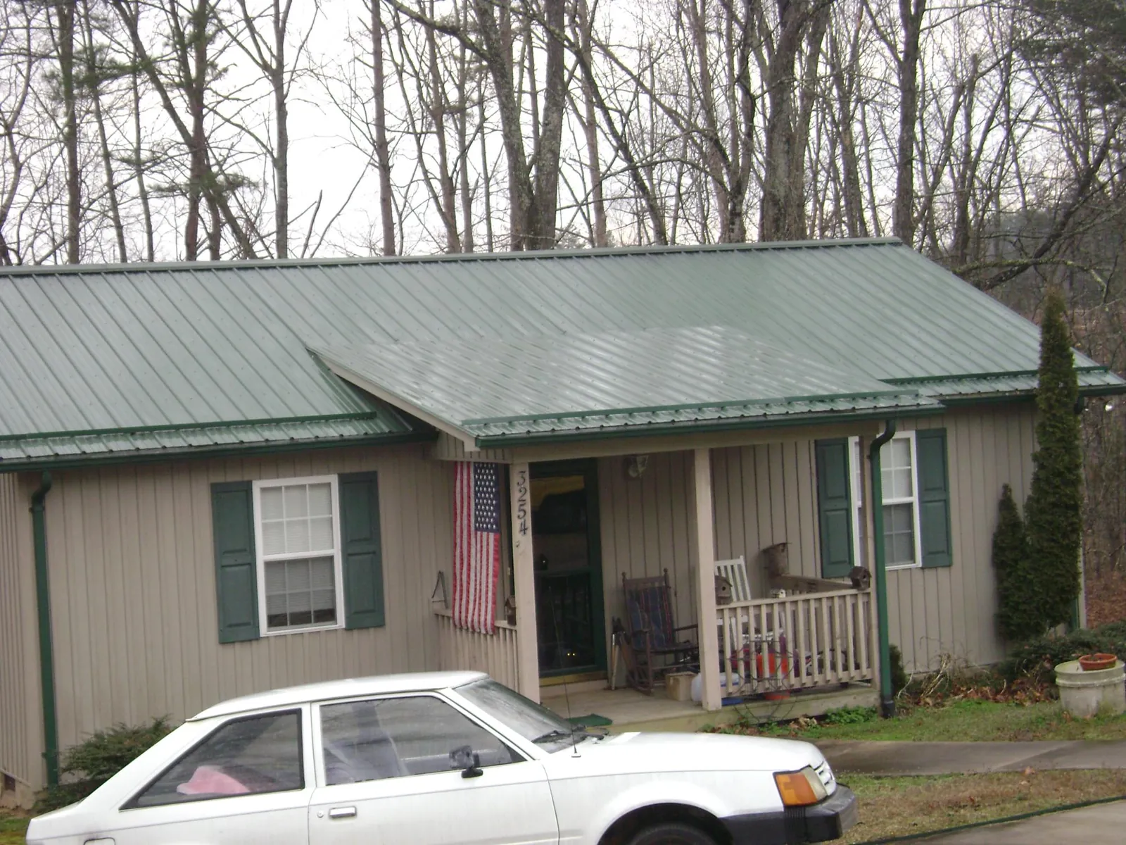 Green metal roof and front porch on a tan sided cottage in Black Diamond