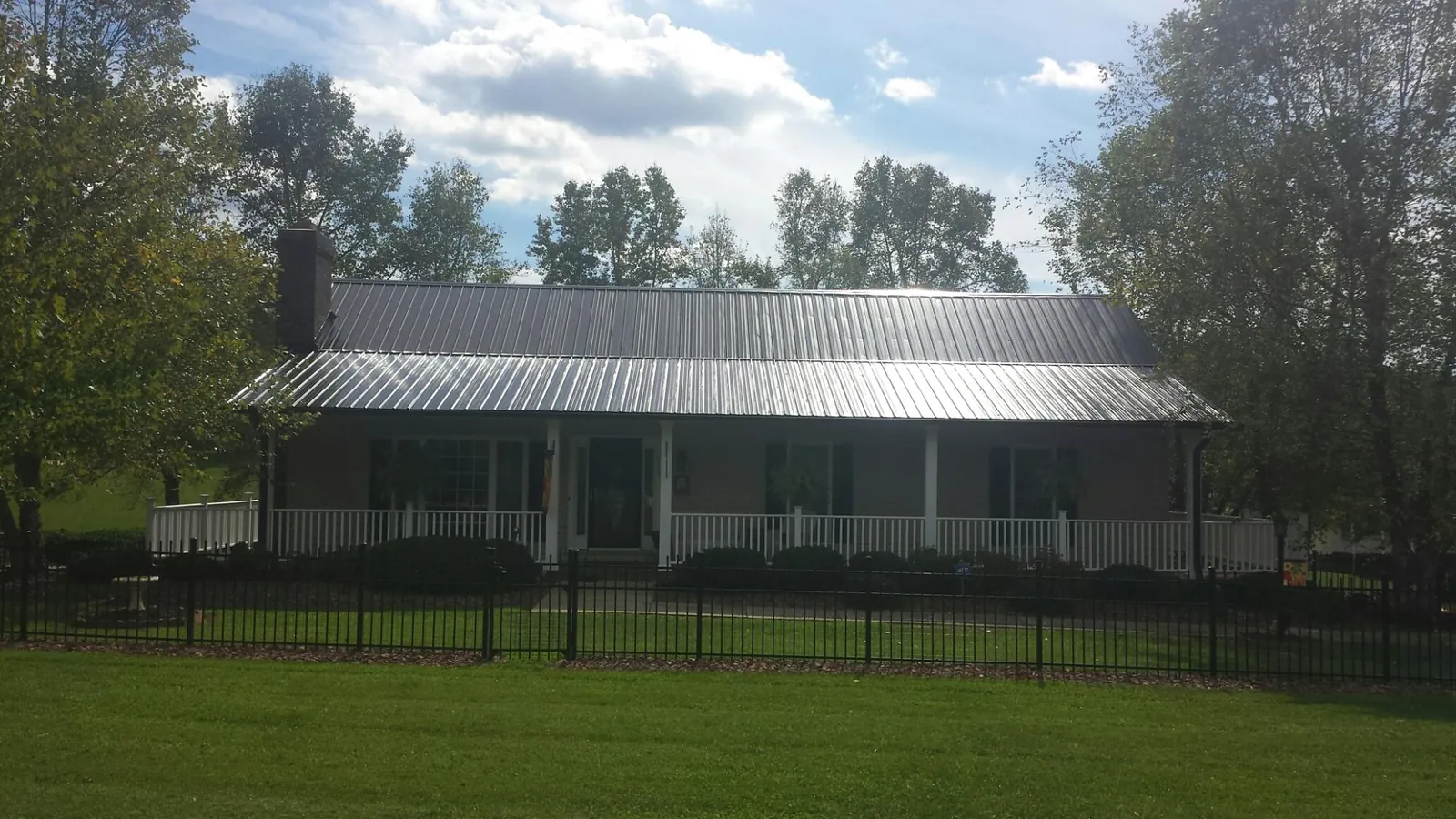 Gray metal roof on a brick ranch with a full width front porch — Gutter Guard Installation work by our crew in Black Diamond