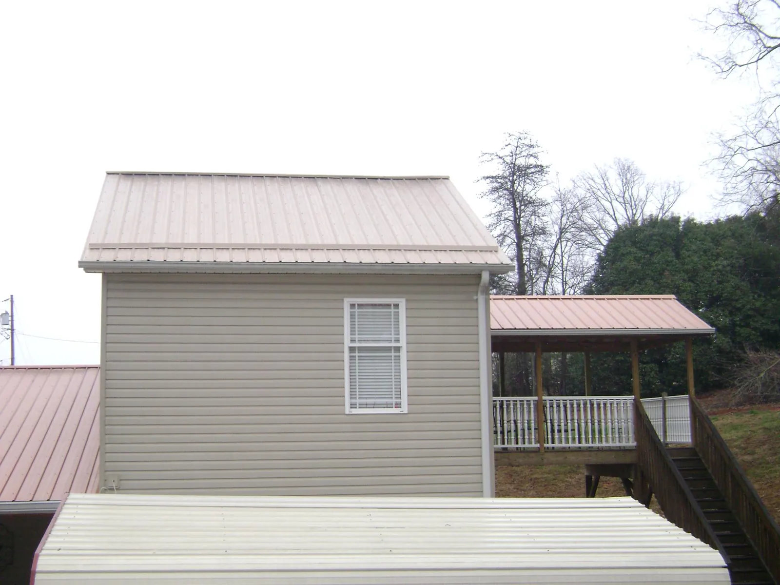 Tan metal roofs on a two story addition and attached porch, from a Roof Replacement job in Black Diamond