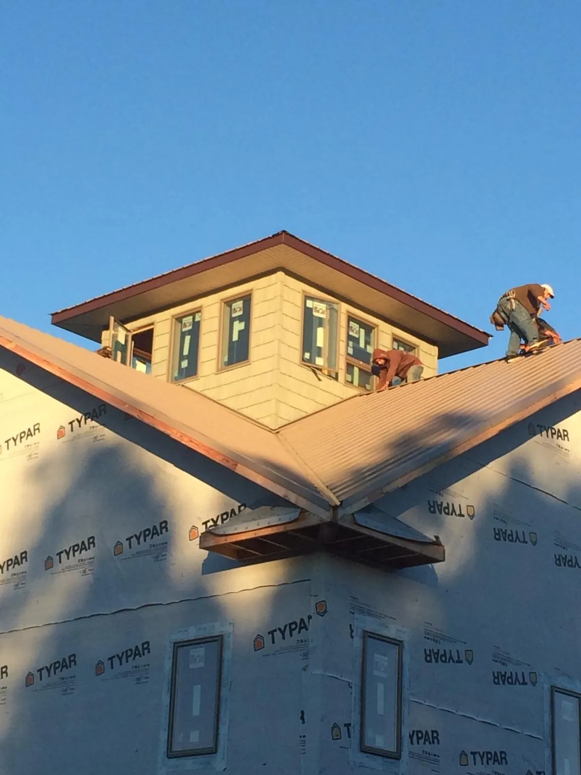 Roofers working around a rooftop cupola on a new metal roof at sunset — Roof Waterproofing in Black Diamond by Roofing Brothers